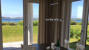 En matplats med ett bord och stolar, utsikt över havet och en gardin.