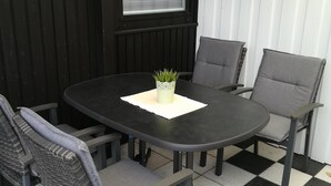 Una mesa redonda con cuatro sillas, una planta pequeña y un cuadro en la pared.