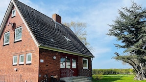 A red brick building with a steeply pitched roof, a small porch, and a bicycle parked outside. - Vacation home Zur Alten Mühle - spacious living in Orth (Schwanitz) with garden & T (Fehmarn)