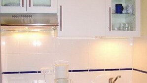 A kitchen with white cabinets, a stainless steel sink, and a coffee maker. - Relax in the cozy vacation apartment on the Baltic Sea in Fehmarn! (Fehmarn)