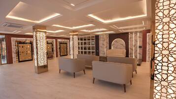 A spacious lobby with modern lighting, marble walls, and seating areas.