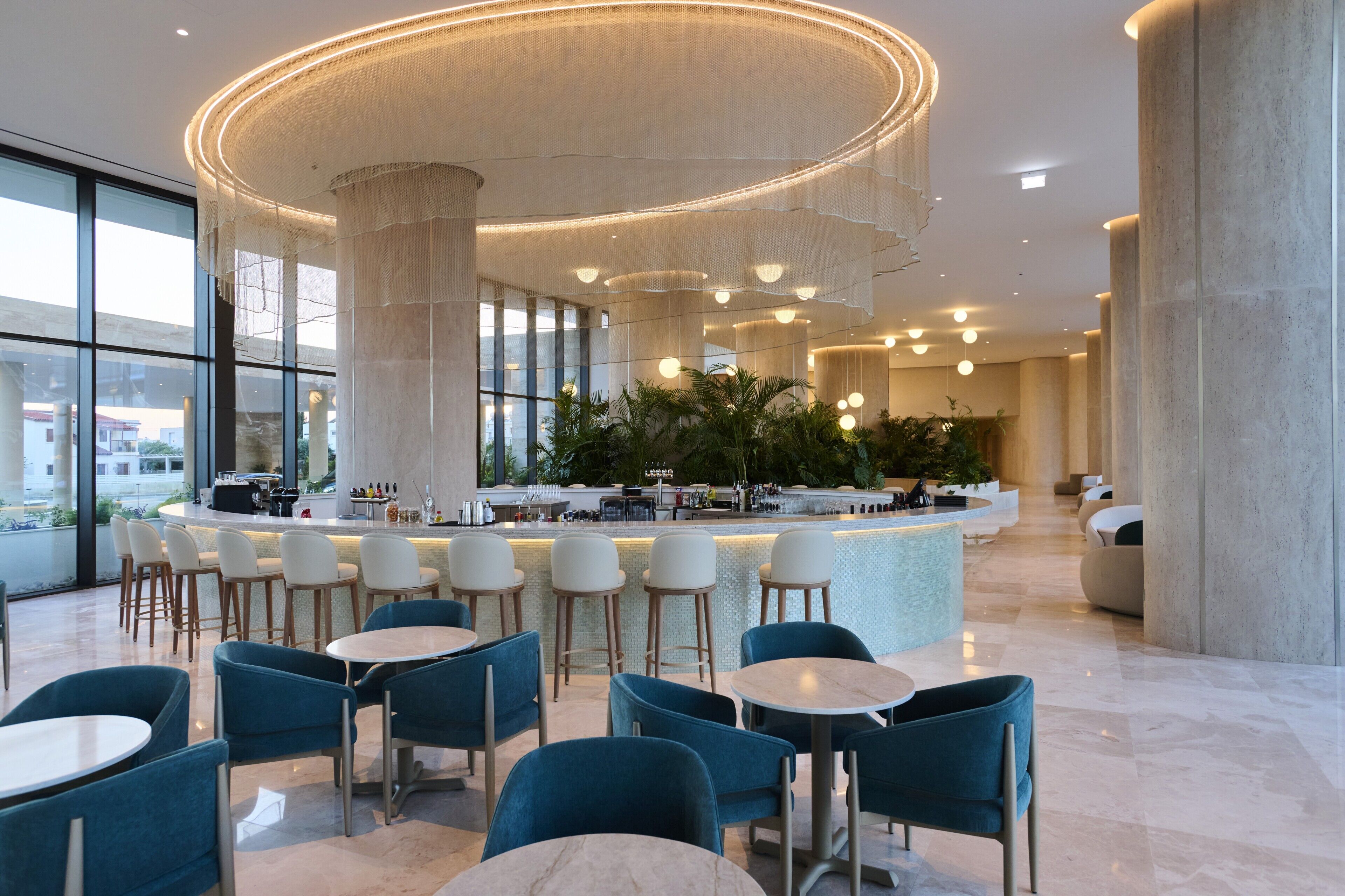 A modern interior with a central bar, seating areas, and large windows.