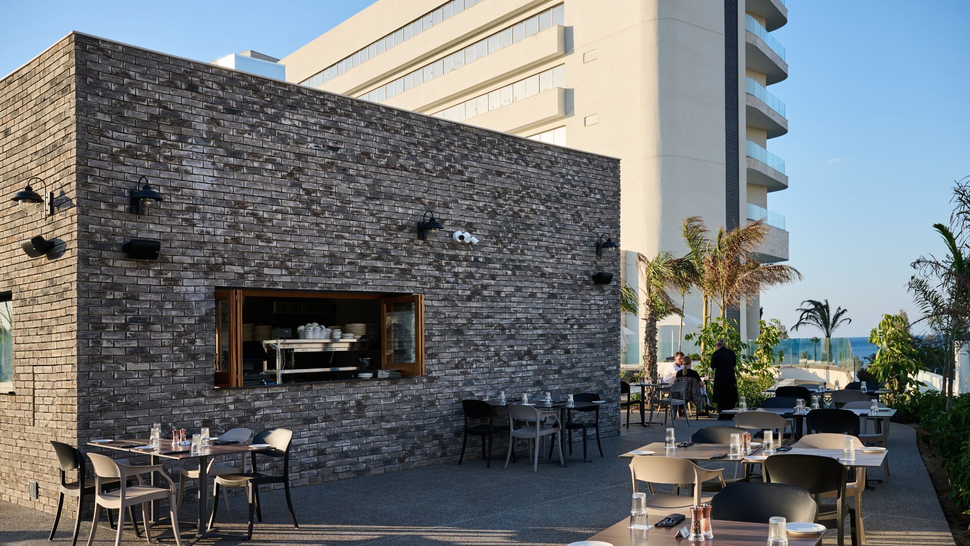 Un área de comedor al aire libre con paredes de ladrillo, mesas y sillas.