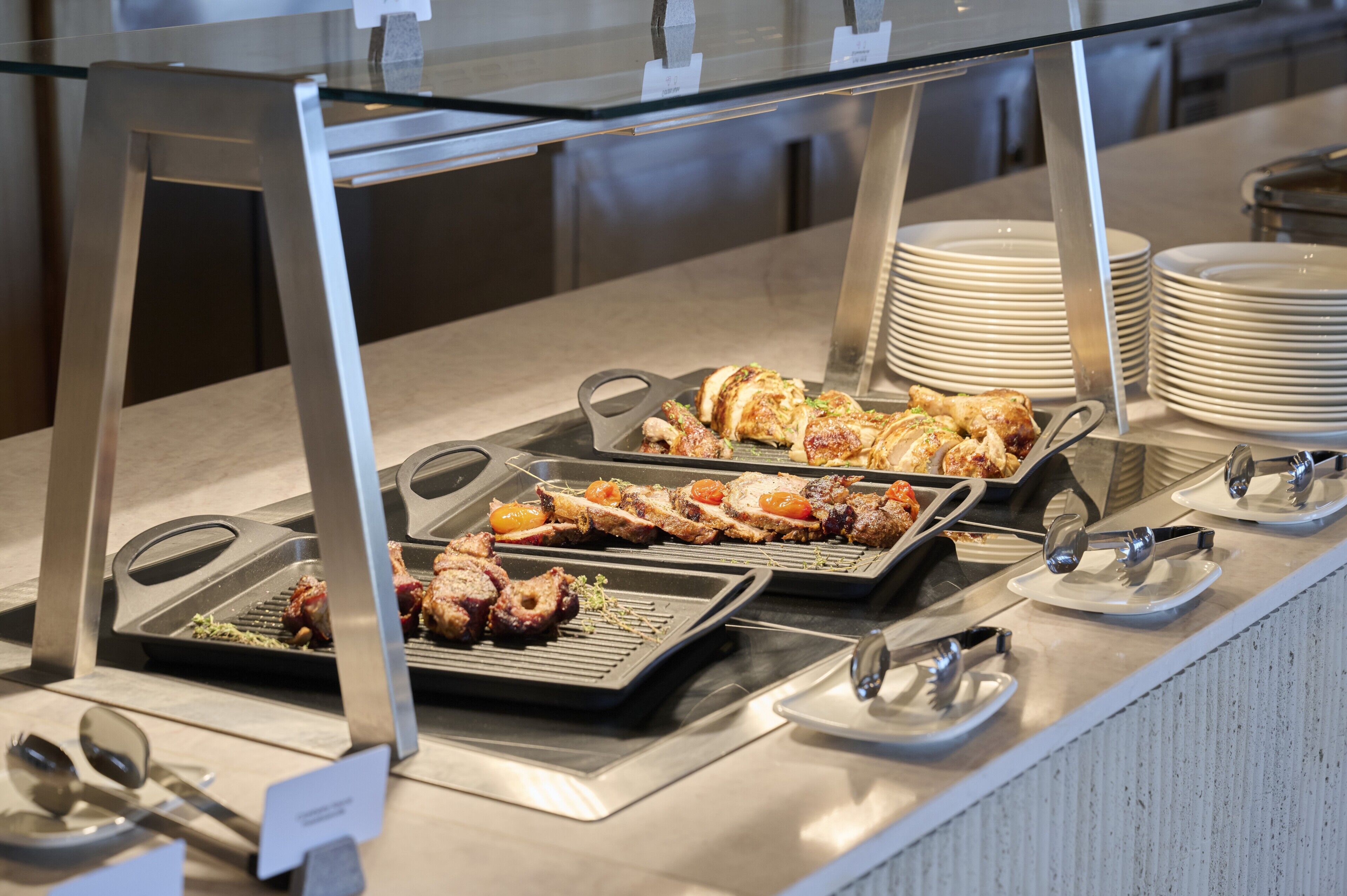 A buffet with various dishes, including meats and vegetables, served on trays.