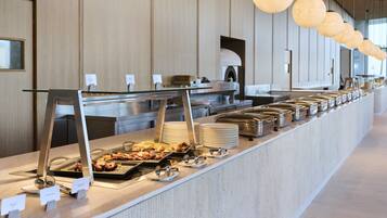 A buffet setup with various food items and serving utensils.