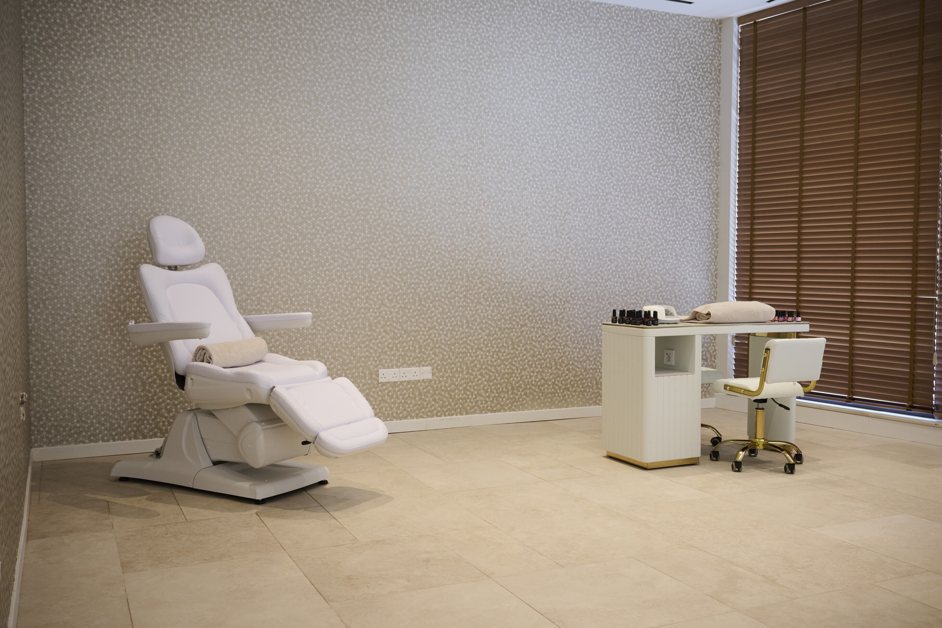 A dental clinic with a reclining dental chair, a desk with a computer, and a chair with wheels.