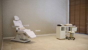 A dental clinic with a reclining dental chair, a desk with a computer, and a chair with wheels.