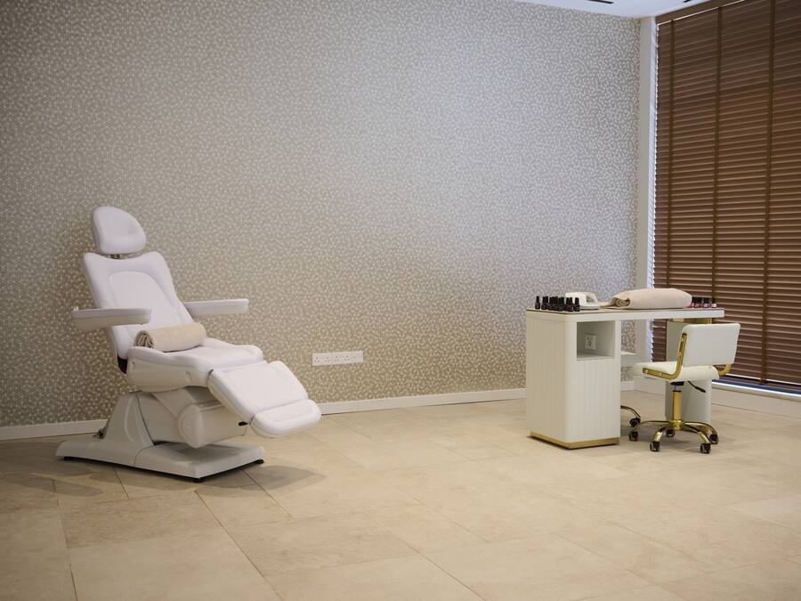 A dental clinic with a reclining dental chair, a desk with a computer, and a chair with wheels.