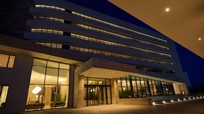 A modern building with multiple floors, large glass windows, and a well-lit entrance. - Sunrise Emerald (Paralimni)
