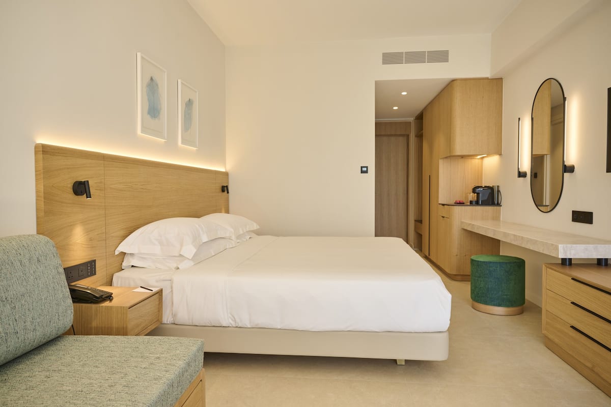 Una habitación de hotel moderna con una cama, un área de descanso, un tocador con espejo y obras de arte en la pared.