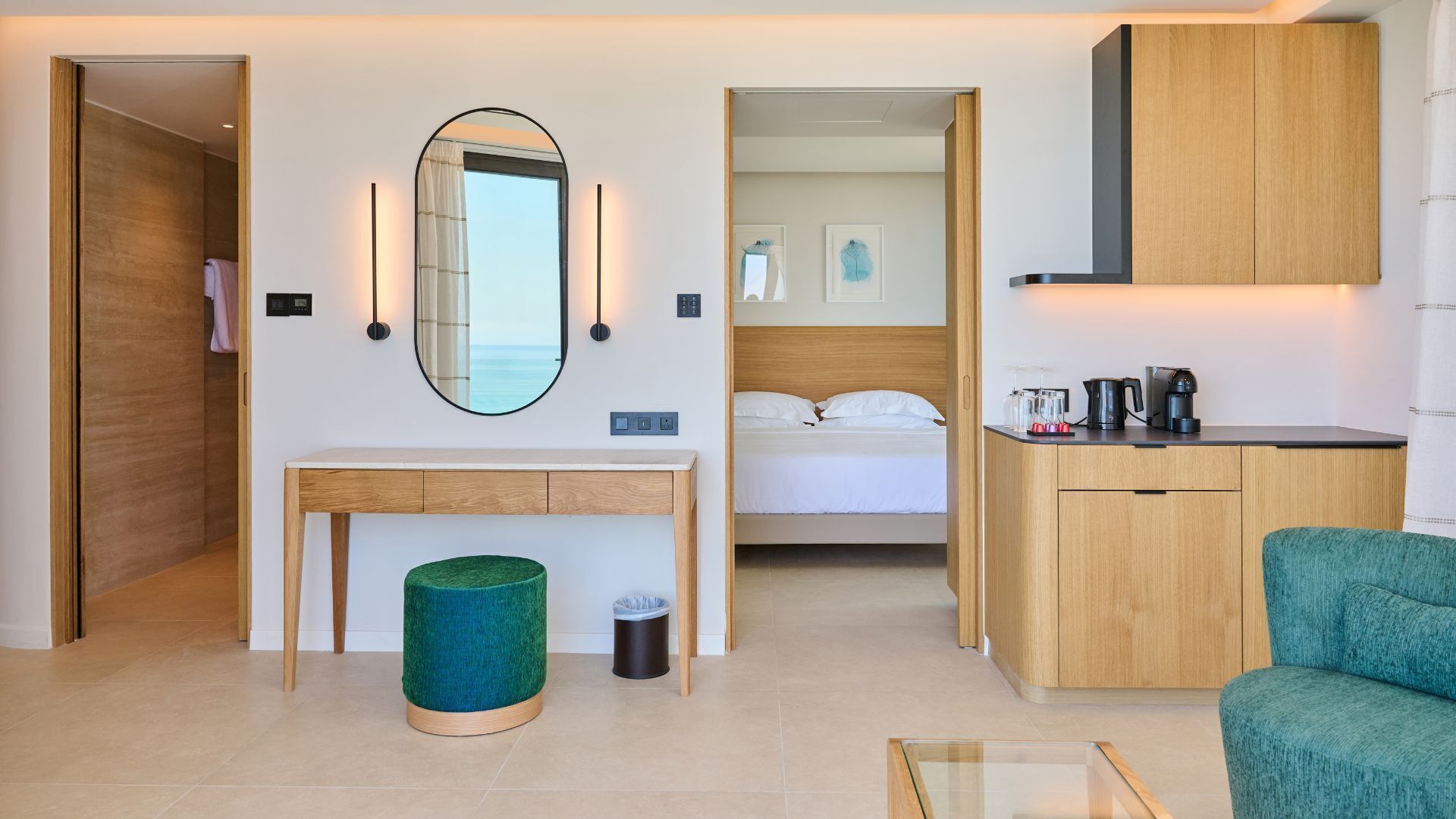 Habitación de hotel con cama, escritorio, espejo, cafetera y cubo de basura.