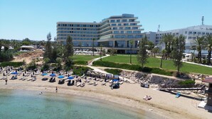 Ein Hotel mit Pool, Strand mit Liegestühlen und freiem Blick auf das Meer.