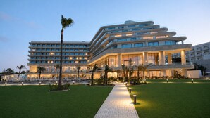 Ein mehrstöckiges Hotel mit Innenhof, Palmen und einem gepflasterten Weg.