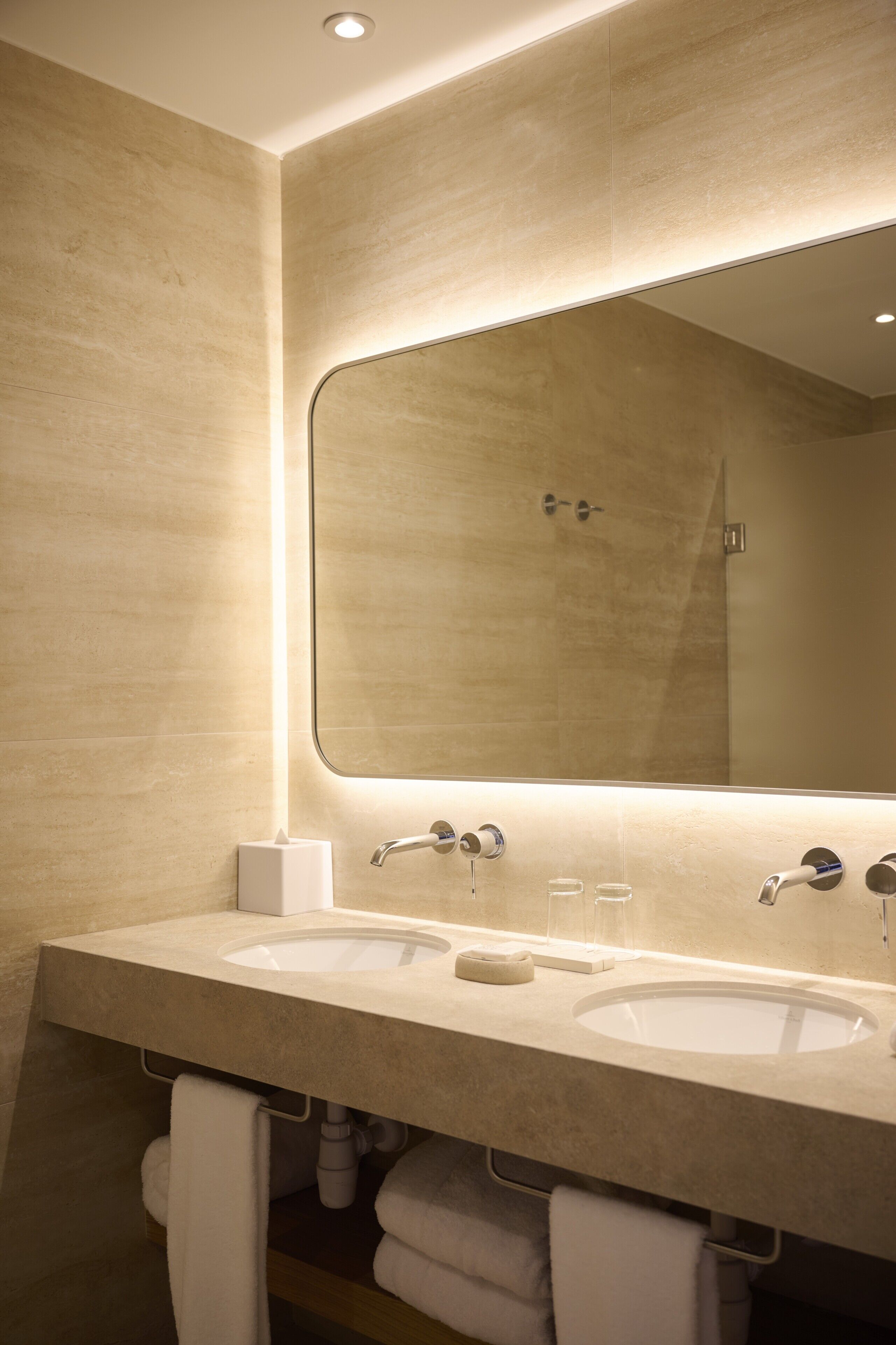 A modern bathroom with two sinks, a large mirror, and a towel rack.