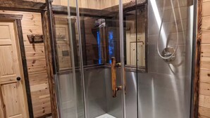 Eine Duschkabine mit Glas, einer Holztür und einem Metallgriff.