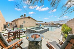 An outdoor patio area with a fire pit, lounge chairs, a pool, and a covered seating area. - 3BR Desert Escape , Pool, Views & Mini Golf (Desert Hot Springs)