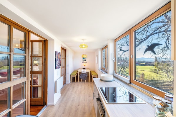 Una habitación larga y estrecha con ventanas amplias, suelo de madera y un banco.