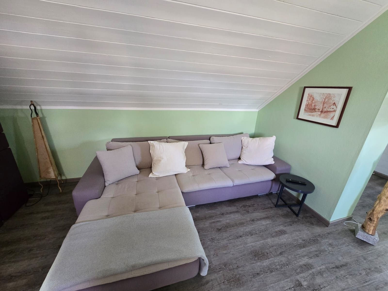 A room with a sofa, a small table, and a framed picture on the wall.