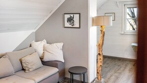 Una habitación con sofá, lámpara, un cuadro enmarcado y una ventana.