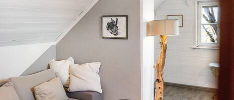 A room with a sofa, a lamp, a framed picture, and a window.