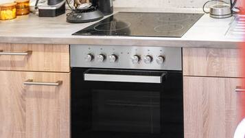 Una cocina equipada con horno integrado, placa de cocción y microondas.