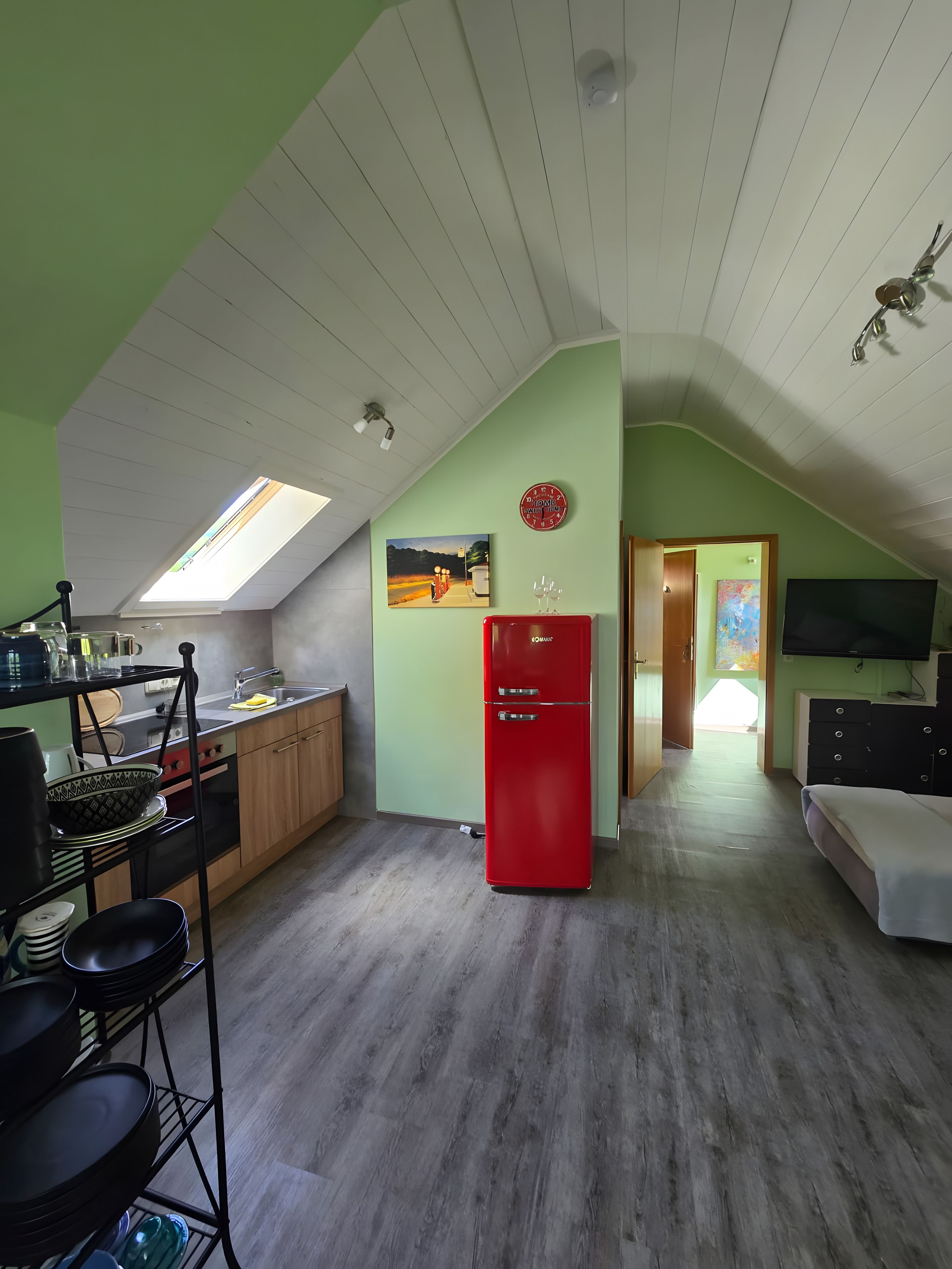 Eine kleine Küche mit einem Oberlicht, einem roten Kühlschrank und einem Essbereich mit Tisch und Stühlen.
