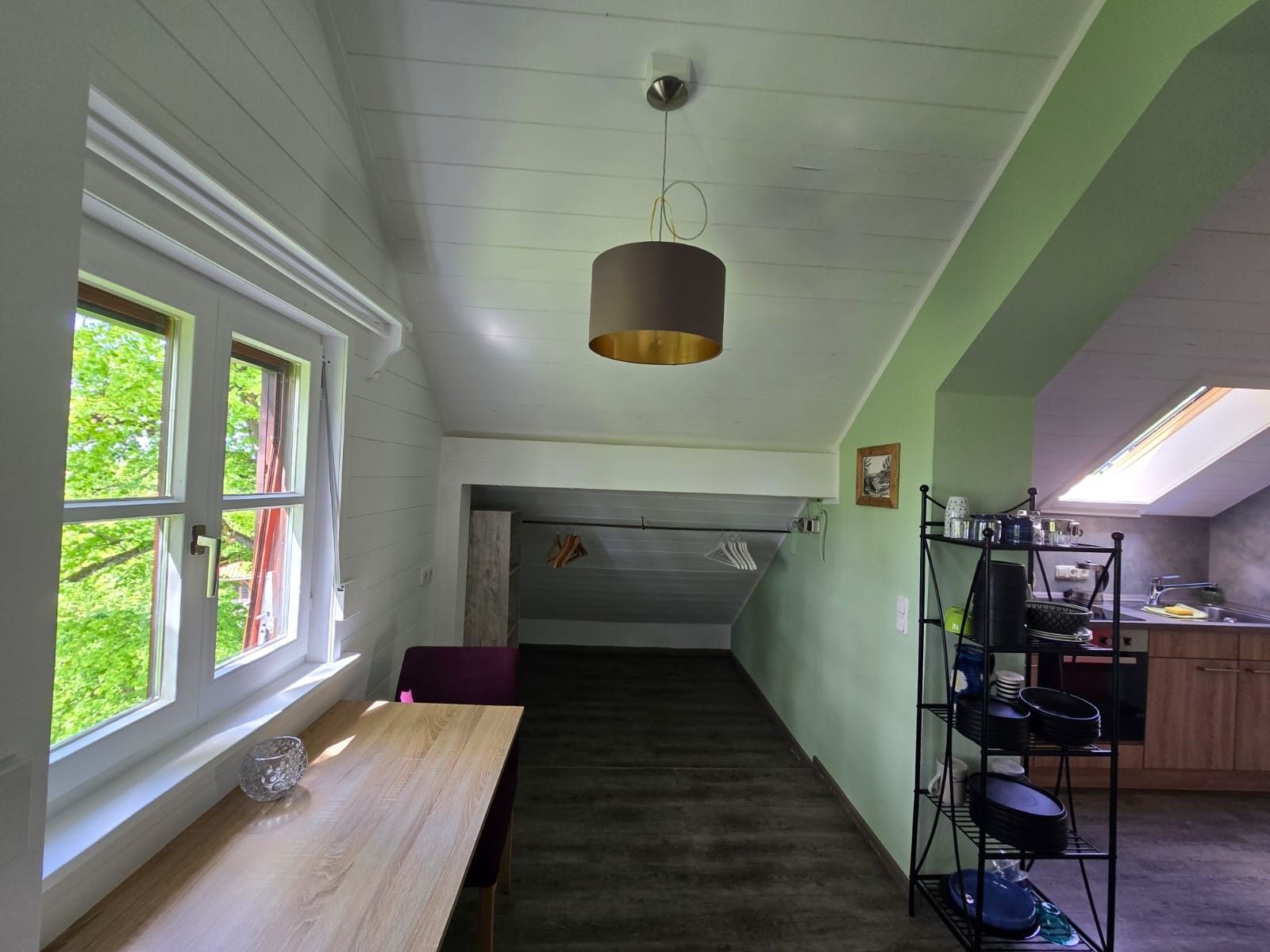 Une cuisine avec un coin repas, un escalier et une vue sur la verdure environnante.