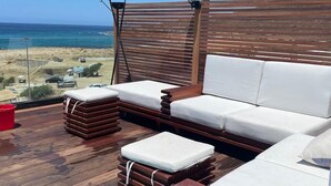 A wooden deck with a white sofa and ottoman, a red bucket, and a view of the ocean. - atico azul (Tangier)