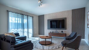 Een moderne woonkamer met een bank, fauteuil en een ronde salontafel.