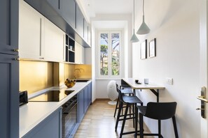 A modern kitchen with a dining area, featuring a window, pendant lights, and a view of the outdoors. - Charming home near San Giovanni (Roma)