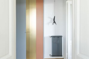 Un pasillo con un radiador, una lámpara colgante y una puerta con diseño de rayas verticales.