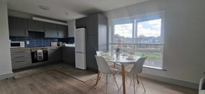 Een koelkast, een oven, een kookplaat, kookgerei, borden en bestek