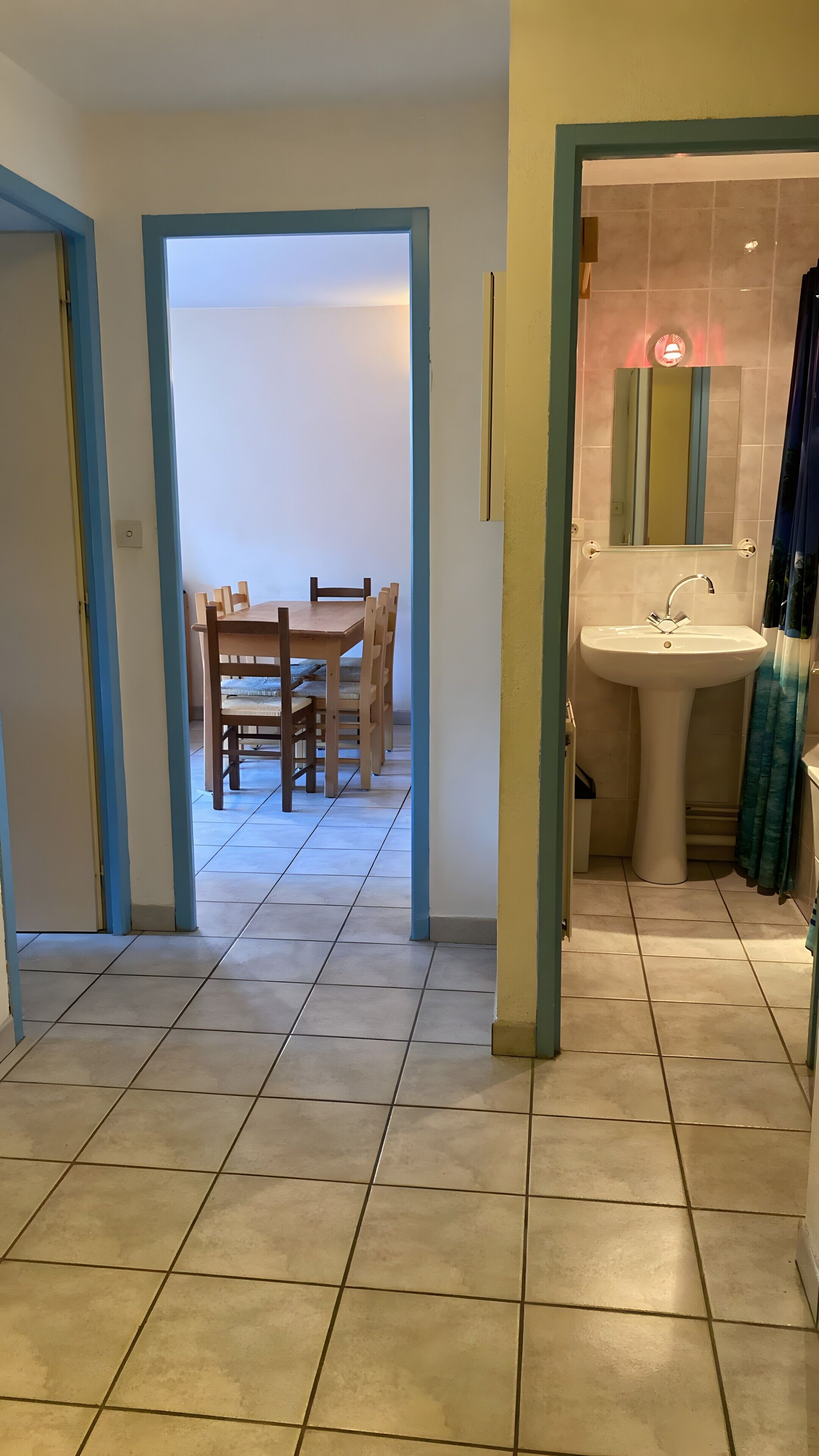 A hallway with a dining area, a sink, and a mirror.