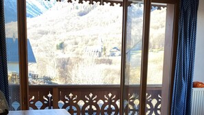 A wooden table with a laptop, a chair, and a view of a mountainous landscape through a glass door. - Apartment with Mountain View and Balcony (Saint-Colomban-des-Villards)
