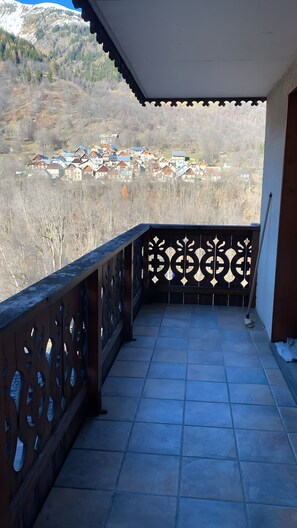 A balcony with a view of a village, a tiled floor, and a decorative railing. - Apartment with Mountain View and Balcony (Saint-Colomban-des-Villards)