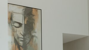 A modern interior with a large abstract painting on the wall, a sleek dark countertop, and a minimalist design. - Casa confortável estilo americana.Perto da praia e perto do centro. (Rio das ostras)