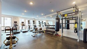 Une salle de sport spacieuse équipée de tapis de course, d’appareils de musculation et d’un espace dédié au sac de frappe.