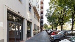 A building with a ground-floor entrance, a parking lot with cars, and trees along the sidewalk. - GuestHost - A comfortable and welcoming 50 square meters apartment, perfect for four people, located on the eighth floor of a building (NO elevator).The property is located in the Washington neighborhood, a lively and well-equipped area of ​​Milan fi (Milan)