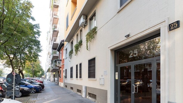 A building with a number 25 sign, parked cars, and a tree-lined street. - GuestHost - A comfortable and welcoming 50 square meters apartment, perfect for four people, located on the eighth floor of a building (NO elevator).The property is located in the Washington neighborhood, a lively and well-equipped area of ​​Milan fi (Milan)
