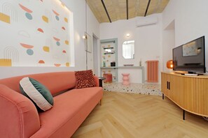 A modern living room with a sofa, TV, and a patterned wall. - Colorful and classy apartment near Fori Imperiali (Roma)