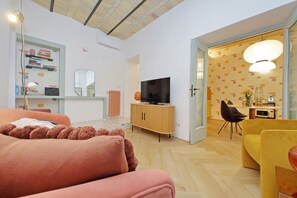 A modern living room with a sofa, a television, and a dining area with chairs and a table. - Colorful and classy apartment near Fori Imperiali (Roma)