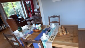 A dining area with a wooden table, chairs, and breakfast items.
