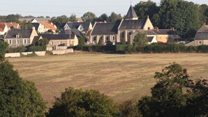A rural village with traditional houses, a church, and a large open field.