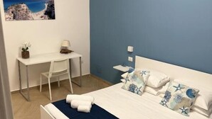 A bedroom with a bed, a desk, and a chair.