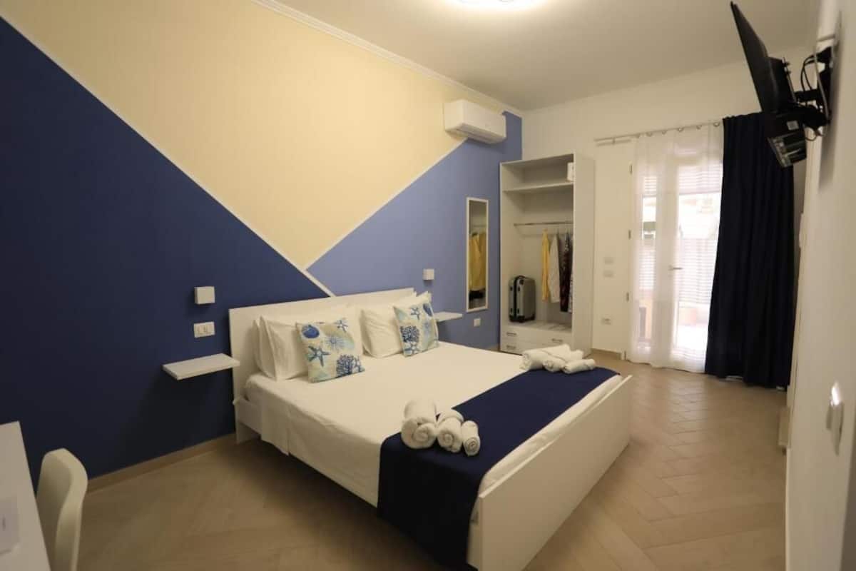 Un dormitorio con cama, armario y baño al fondo.