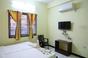 A hotel room with a bed, curtains, a chair, a TV, and a small table. - Lakshmi Palace Near MGR Bus Stand (Madurai)