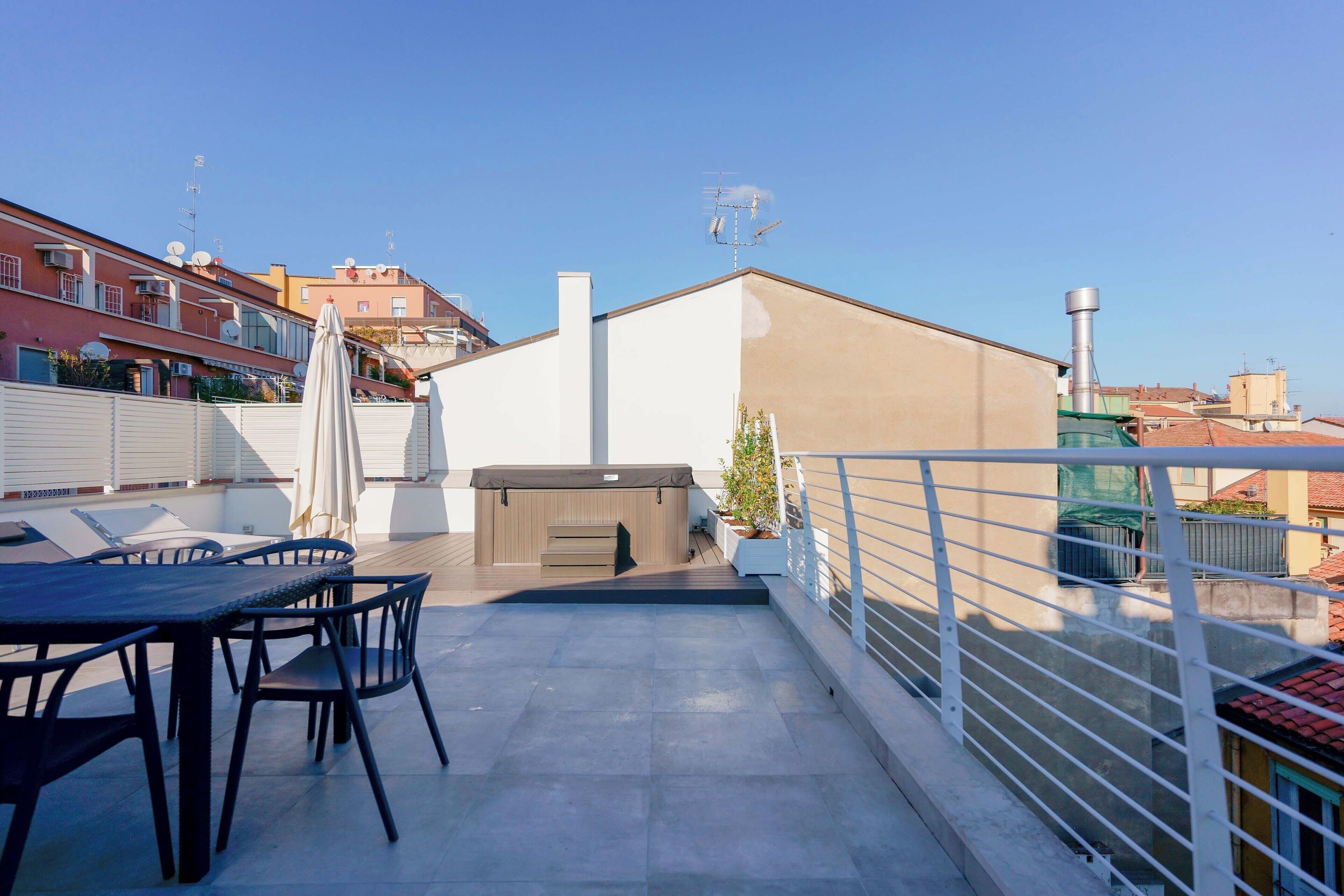 Une terrasse sur le toit, avec une table et des chaises, un espace barbecue et une vue sur les bâtiments environnants.