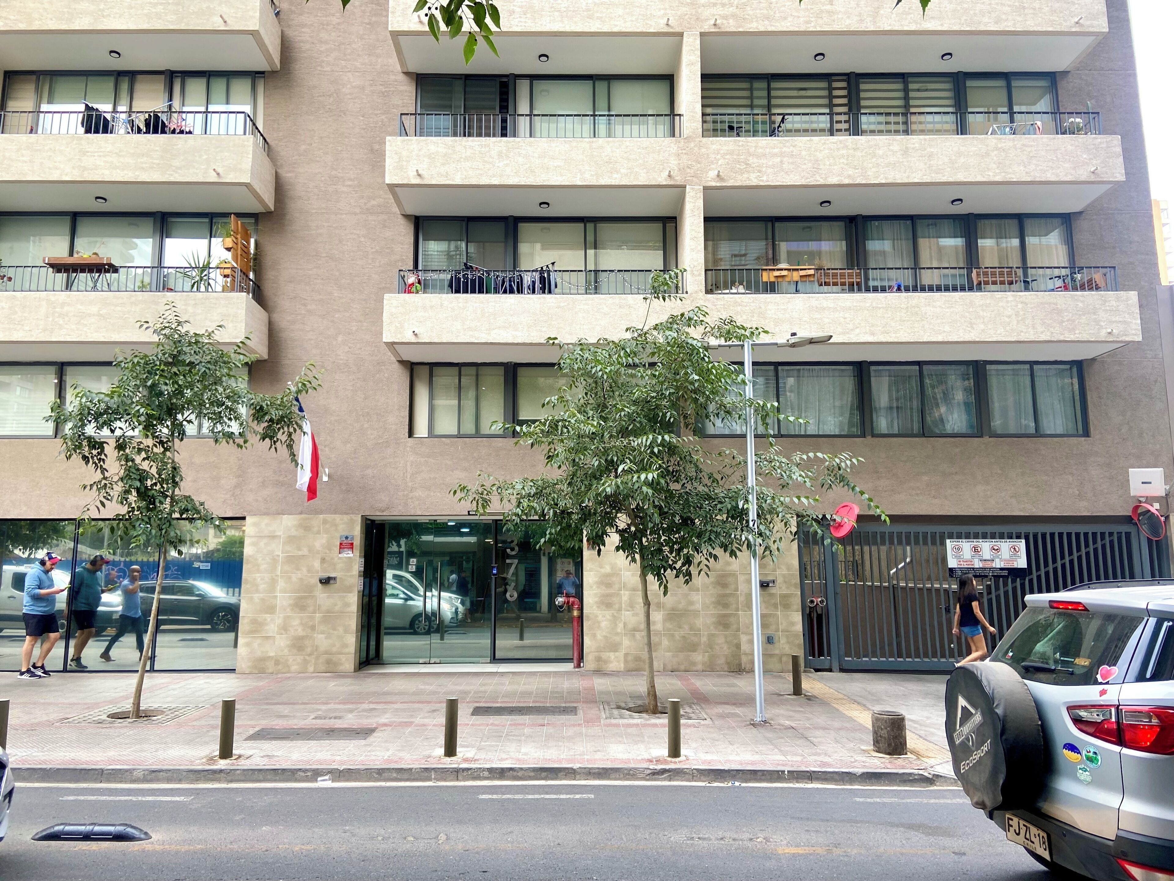 Een meerlaags gebouw met balkons, een hekpoort en een parkeerplaats.