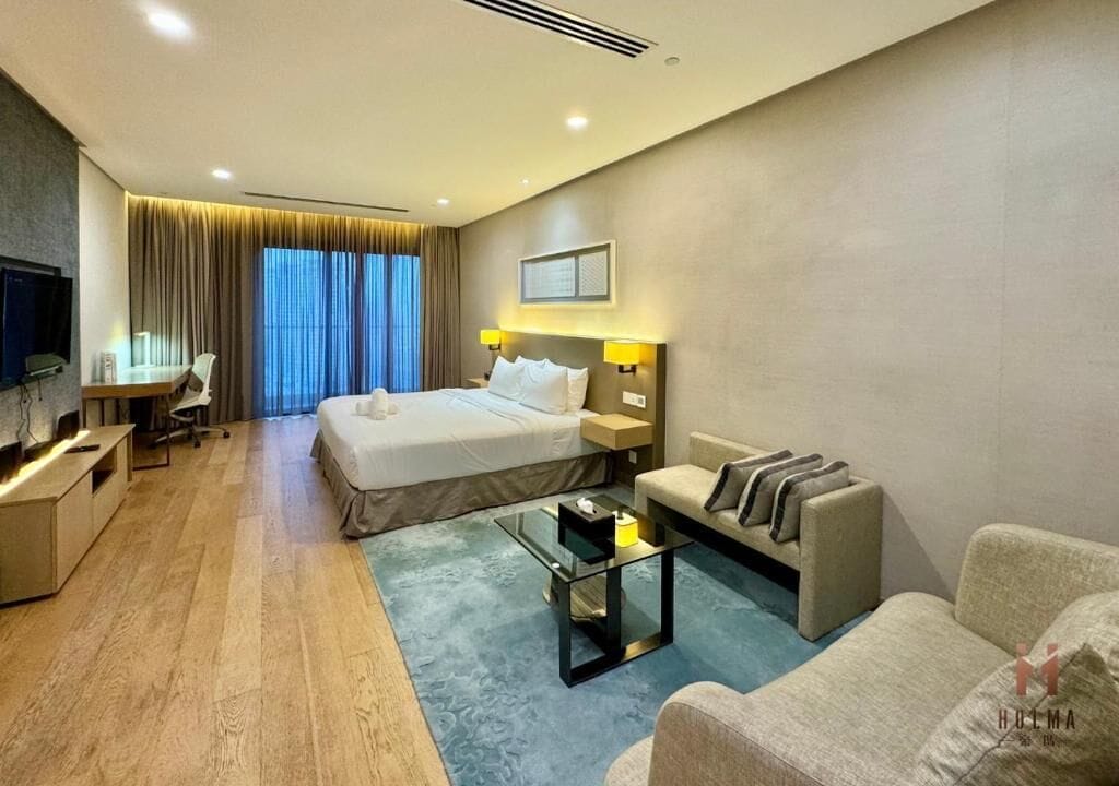 A hotel room with a bed, a sofa, a desk, and a TV.