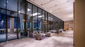 A modern hotel lobby with a long reception desk, glass walls, and a seating area with sofas and armchairs. - Signature Apartment at 188 Suites (Kuala Lumpur)